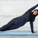 Perempuan berhijab tengah melakukan olahraga ringan.