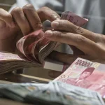 Teller menghitung sejumlah uang Rupiah.