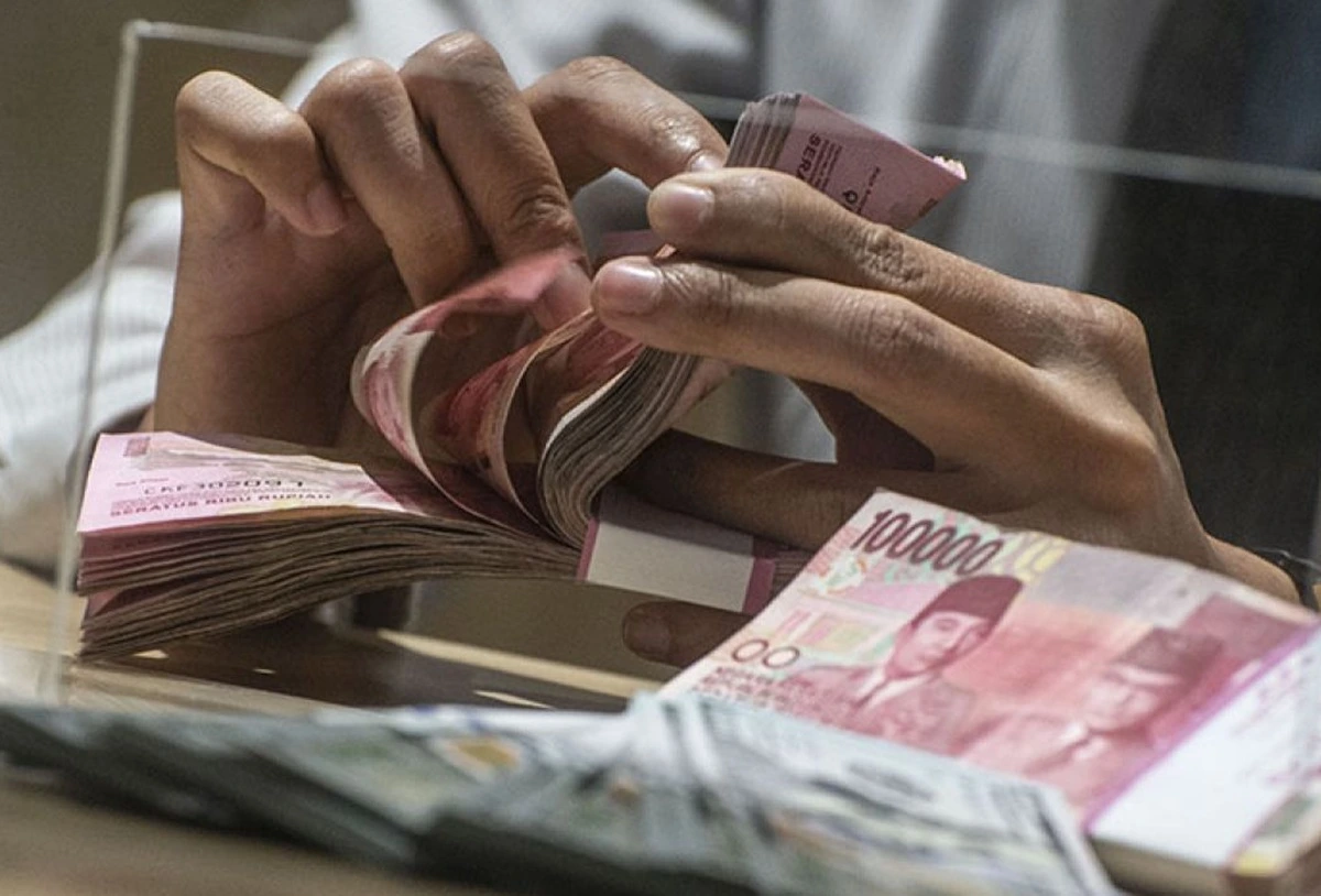 Teller menghitung sejumlah uang Rupiah.