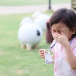 Anak perempuan memegang masker tengah batuk.(freepik)