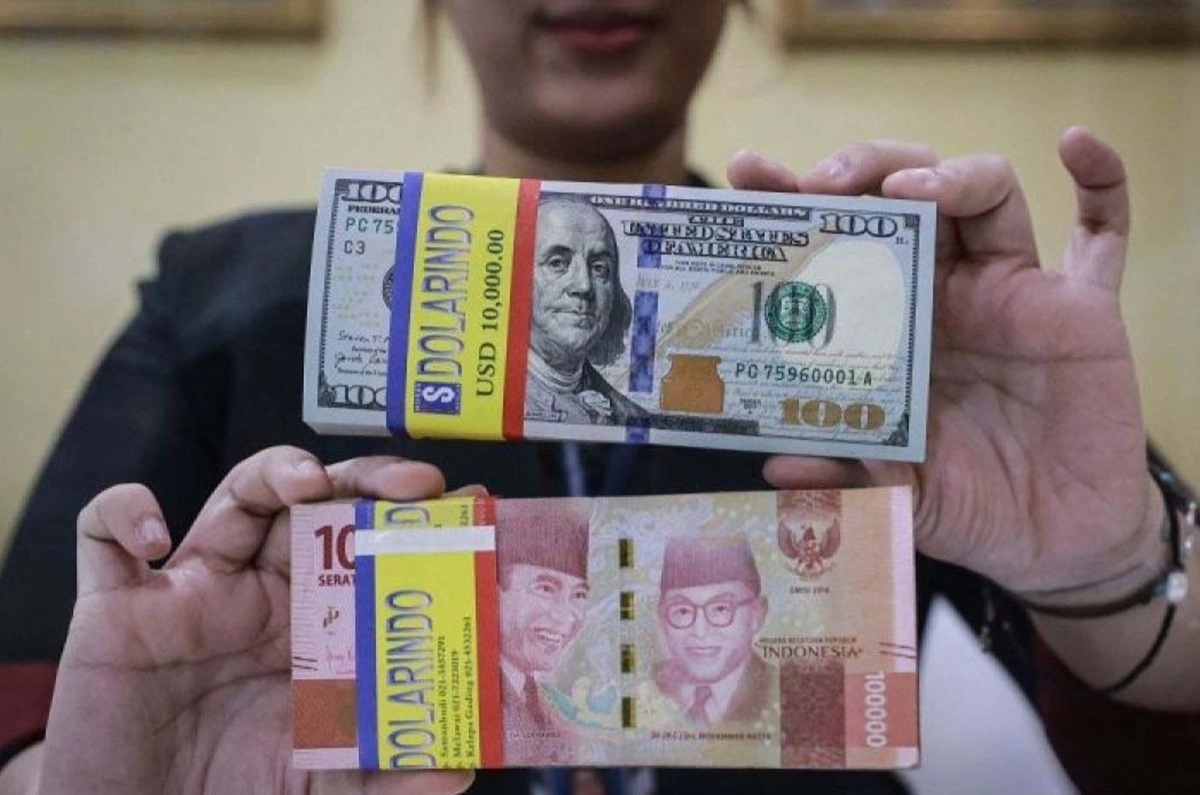 Teller memegang uang Rupiah dan Dolar AS.