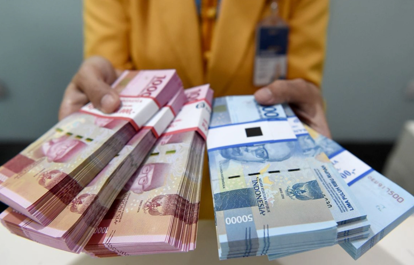 Teller memegang tumpukan uang rupiah.(Antara)