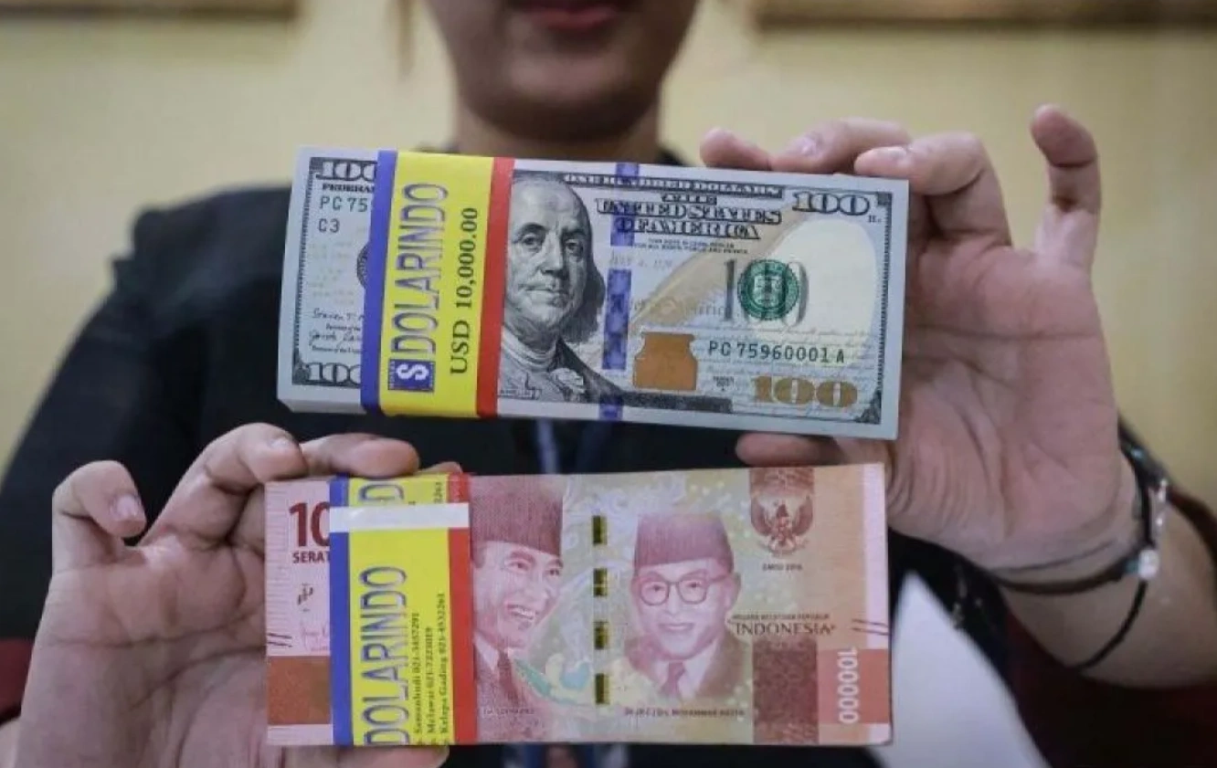 Teller bank memegang uang Rupiah dan Dolar AS.